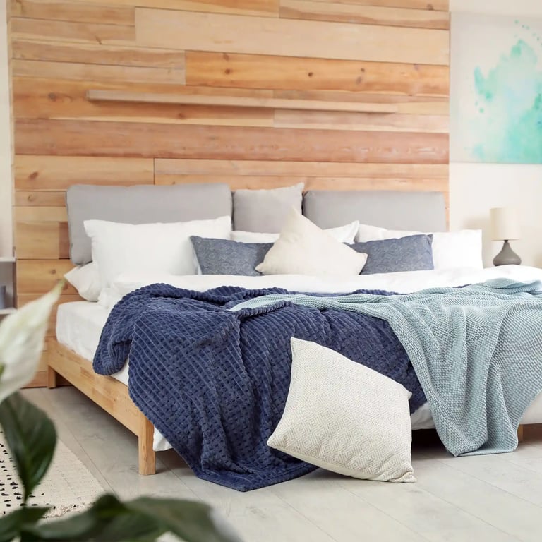 Bett mit vielen Kissen und Tagesdecke, alles in Beige- und Blautönen