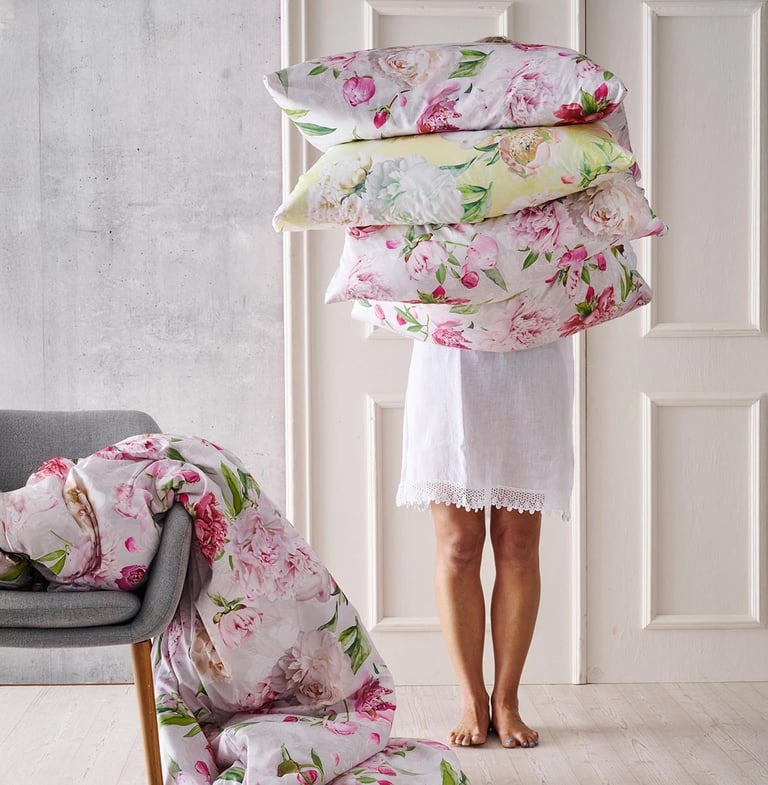 Frau die Blumenbettwäsche in den Armen hält