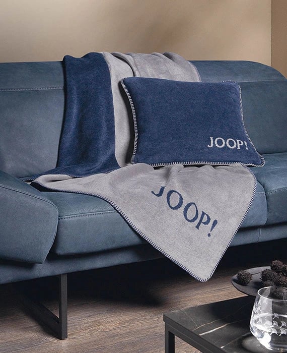 Wohndecke und Dekokissen in blau auf einem Sofa